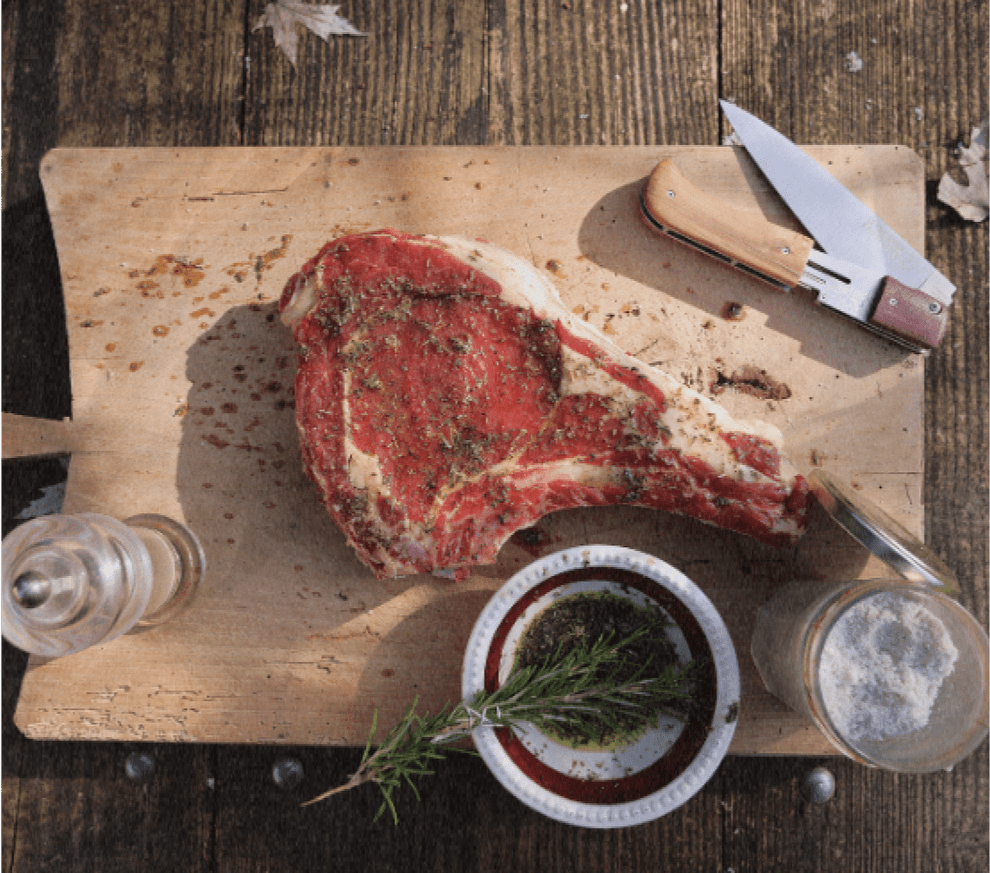 Côte de bœuf et couteau Le Cuisinier Français sur planche en bois